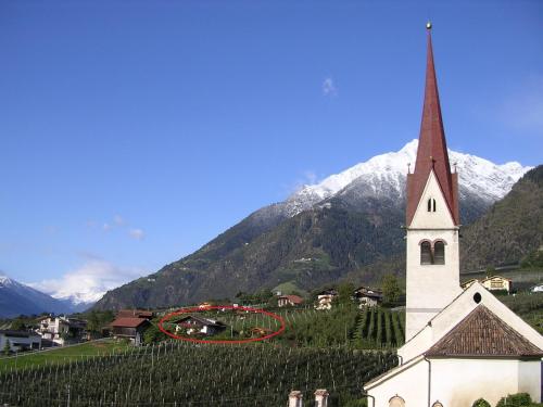 a church with a red circle on it in front of mountains at Oberangerhof in Lagundo