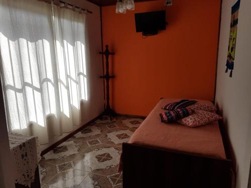 a bedroom with an orange wall with a bed and a window at Las Casitas de Emilia in Ramallo