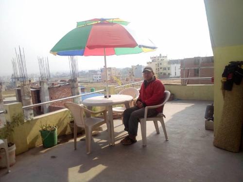 a man sitting at a table under an umbrella at Everest Home Stay Apartment in Pātan