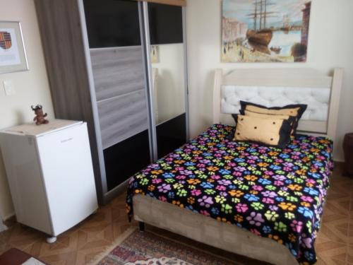 um quarto com uma cama com um edredão colorido em Praia (pé na areia) em Mongaguá para casal em Mongaguá