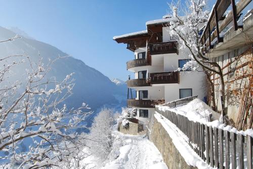 a building covered in snow with mountains in the background at Apart Stotter in Kappl