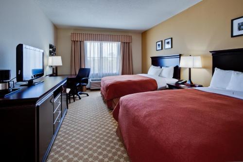 Country Inn & Suites by Radisson, Port Orange-Daytona, FL في بورت أورنج: غرفة فندقية بسريرين وتلفزيون بشاشة مسطحة