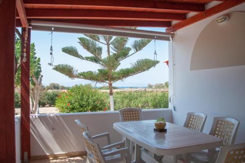 a table and chairs on a balcony with a palm tree at Felicia's sun-side house in Kastraki Naxou