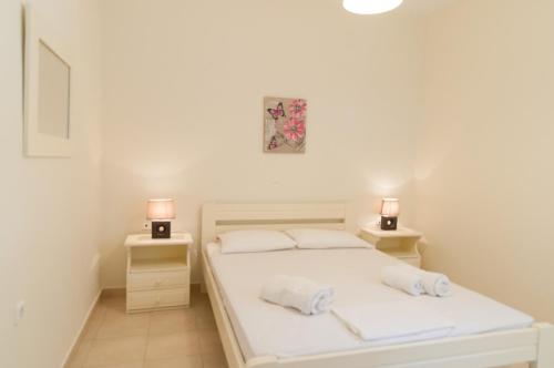 1 dormitorio con 1 cama blanca y 2 mesitas de noche en Felicia's sun-side house, en Kastraki Naxou