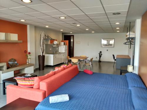 sala de estar con sofá rojo y cama azul en Studio Loft Fuerteventura, en Puerto del Rosario