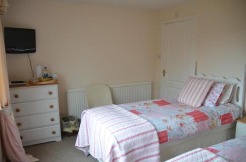 a bedroom with a bed and a dresser at Woodland Guesthouse in Stow on the Wold