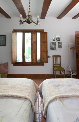 two beds in a room with a window and a chandelier at Las 9 Candelas alojamiento en el centro de Yecla in Yecla