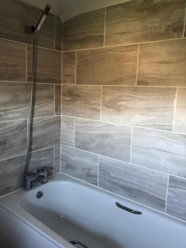 a white bath tub in a bathroom with wooden walls at Fossewold Cotswold Barn in Chipping Campden