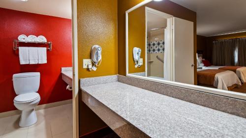 a bathroom with a toilet and a room with a bed at SureStay Hotel by Best Western Camarillo in Camarillo