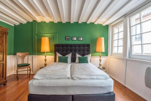 a bedroom with a bed with green walls and two lamps at Apartment Zentral im Herzen der Altstadt in Tübingen