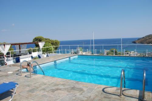 a large blue swimming pool with a view of the ocean at Galini Hotel in Agia Marina Aegina
