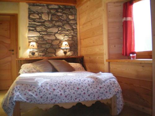 a bedroom with a bed with a stone wall at Au Coeur in Verrayes