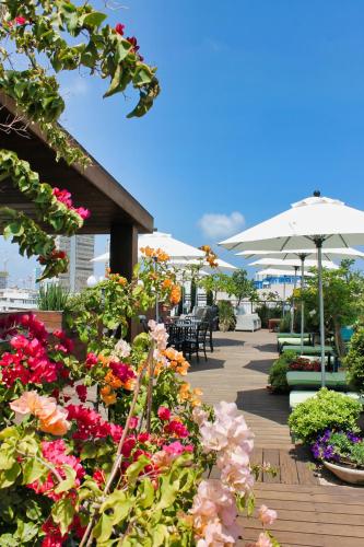 a patio with flowers and umbrellas and tables and chairs at Center Chic Hotel - an Atlas Boutique Hotel in Tel Aviv