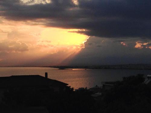 a sunset over a body of water with the sun setting at SEMIRAMIS SUITES with pool in Kalamata