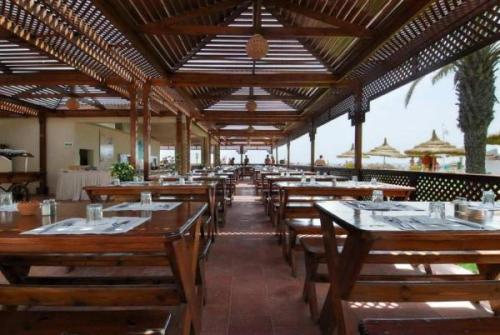 El AhmarにあるSol Palmeras Beach - Family Hotelの木製のテーブルと椅子が置かれた空のレストラン