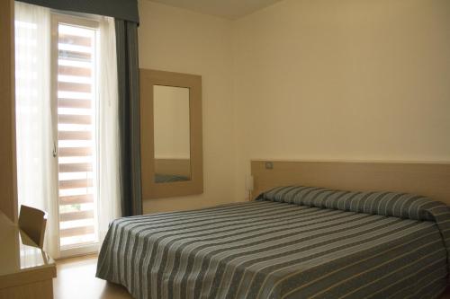 Aparthotel Royal في ليدو دي يسولو: غرفة نوم بسرير ومرآة ونافذة
