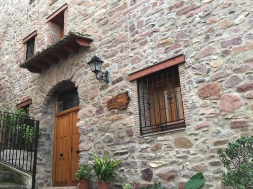 EslidaにあるL' Artesà Turisme Ruralの木製のドアと窓のある石造りの建物