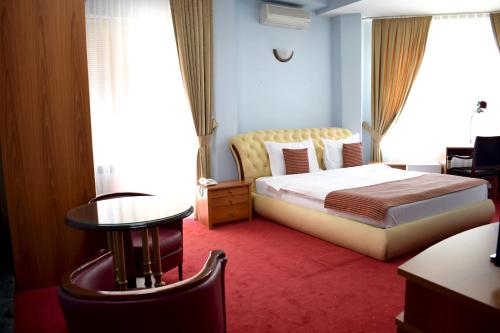 sypialnia z łóżkiem, stołem i oknem w obiekcie Hotel Aristocrat & Fish Restaurant w mieście Skopje