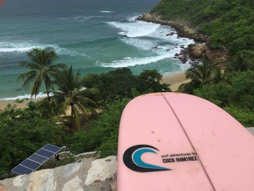 a surfboard sitting on top of a cliff overlooking a beach at Paziflora Hostel -STARLINK- in Puerto Escondido