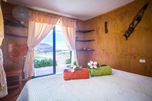 una camera da letto con un letto e una grande finestra di Cabañas & Hostal Tojika a Hanga Roa