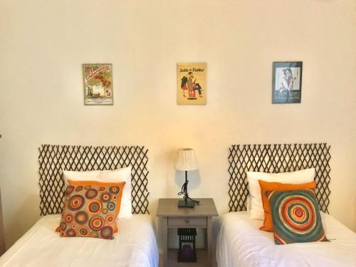 リスボンにあるCharming Flatのベッド2台、テーブル、壁の絵画が備わる客室です。