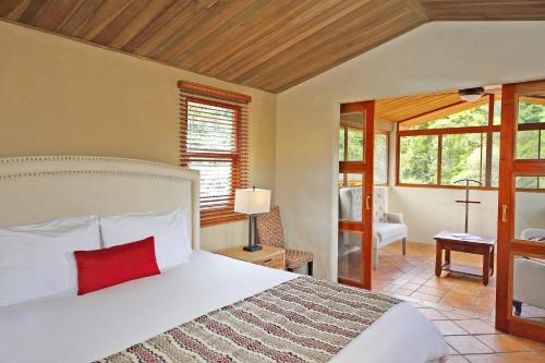 een slaapkamer met een groot wit bed met een rood kussen bij Los Establos Boutique Resort - All Inclusive in Boquete