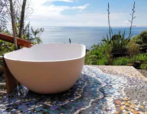 a white bath tub sitting on a table with the ocean at Knights in Residence in Tutukaka