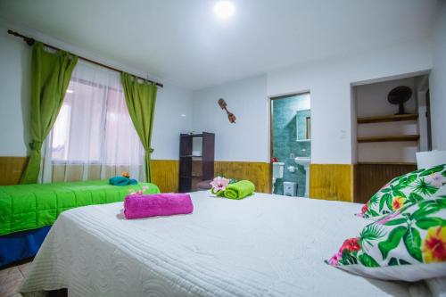 a bedroom with a large white bed with towels on it at Cabañas & Hostal Tojika in Hanga Roa