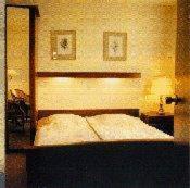 a bedroom with a bed with a wooden head board at Hotel de Admiraal in Noordwijk aan Zee