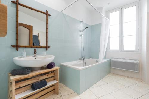 bagno con lavandino, vasca e specchio di Bright Apartment Old Town a Nizza