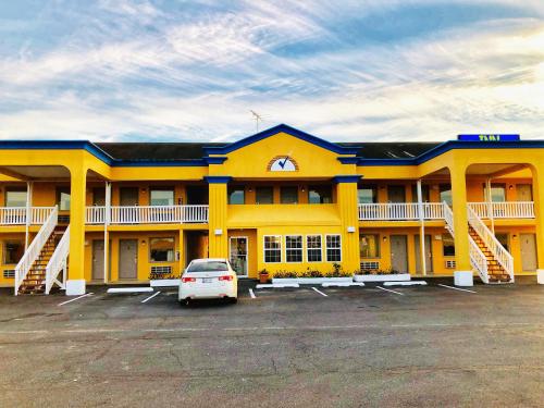 a yellow building with a car parked in a parking lot at Americas Best Value Inn-Princess Anne in Princess Anne