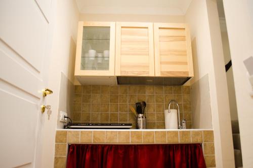 cocina con armarios de madera y cortina roja en B&B Sosta Flegrea en Nápoles