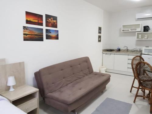 un sofá marrón en una sala de estar con cocina en Acácia Jurerê, en Florianópolis