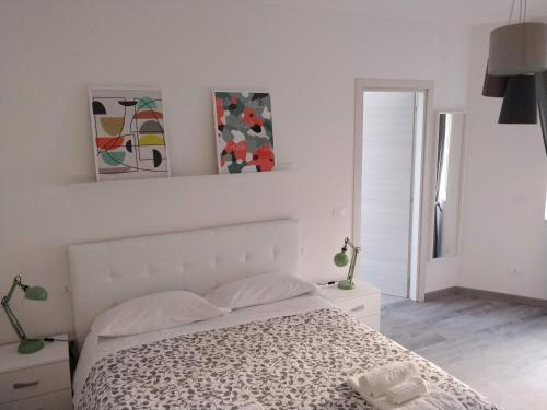 坎波巴索的住宿－Novantatrè，白色卧室配有一张床,墙上挂有绘画作品