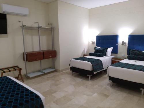 a hotel room with two beds and a dresser at Hotel Dorado La 70 in Medellín