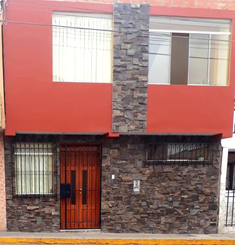 a red building with a stone wall and a door at El Marquez in Tacna