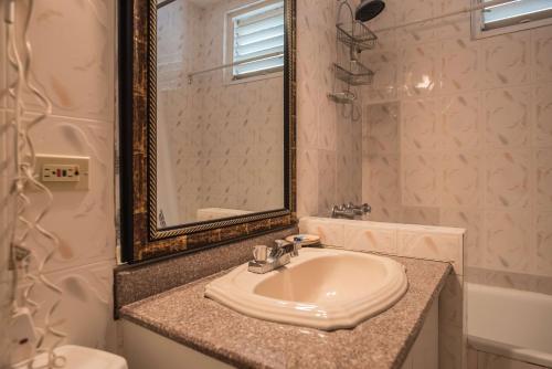 a white bathroom with a sink and a mirror at Sandcastles Beach Suites in Ocho Rios