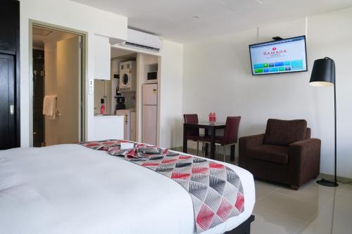 a bedroom with a bed and a chair and a tv at Ramada Suites by Wyndham Wailoaloa Beach Fiji in Nadi