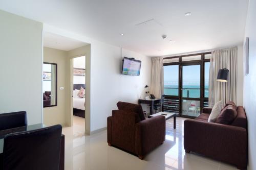 a living room with two chairs and a living room with the ocean at Ramada Suites by Wyndham Wailoaloa Beach Fiji in Nadi