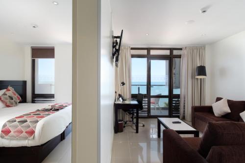 a bedroom with a bed and a living room with a desk at Ramada Suites by Wyndham Wailoaloa Beach Fiji in Nadi