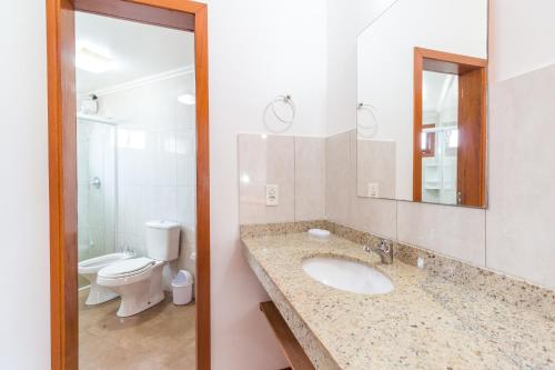 a bathroom with a sink and a toilet and a mirror at Condominio Vila Lila in Garopaba