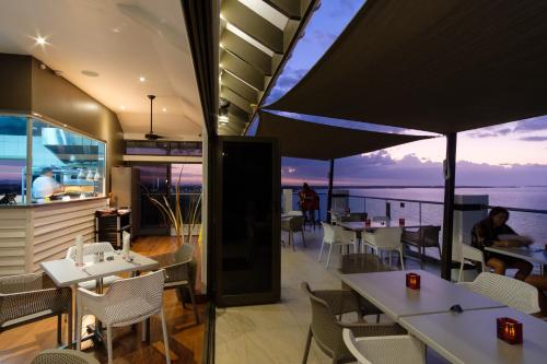 a restaurant with tables and chairs and a view of the ocean at Ramada Suites by Wyndham Wailoaloa Beach Fiji in Nadi