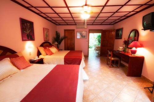 a hotel room with two beds and a desk at El Tucano Resort & Thermal Spa in Quesada