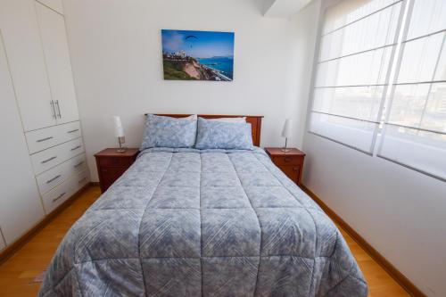 1 dormitorio con 1 cama grande con almohadas azules en Miraflores4Rent Alcanfores en Lima