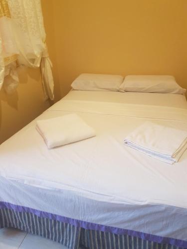 two beds in a room with white sheets and towels at Stella'z guesthouse in Siquijor