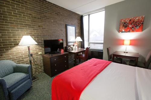 a hotel room with a bed and a chair and a television at Rutgers University Inn and Conference Center in New Brunswick