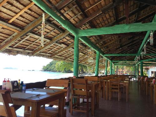 Koh Ngai Resort في كو نغاي: مطعم بطاولات وكراسي خشبية وجام ماء