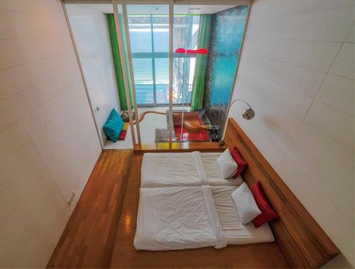 a small room with a bed on a wooden floor at Haslla Art World Museum Hotel in Gangneung