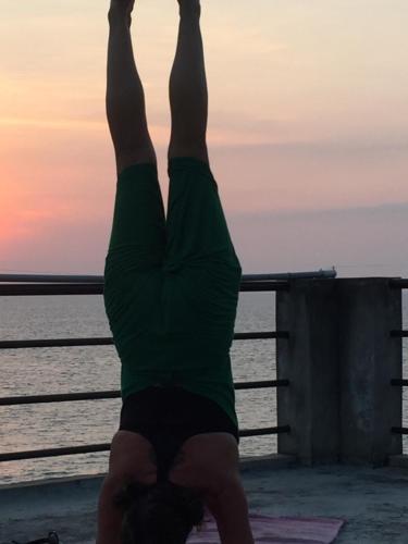 a person doing a handstand in front of the water at The Ocean Park Beach Resort in Kovalam