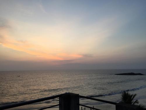 a view of the ocean at sunset from a balcony at The Ocean Park Beach Resort in Kovalam